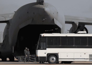 Un avión militar espera a migrantes que suben a un autobús en Fort Bliss en El Paso, Texas, el 30 de enero de 2025, antes de deportarlos a Guatemala.