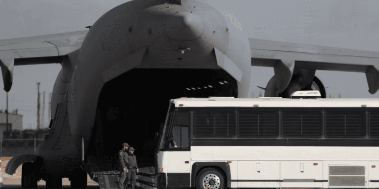Un avión militar espera a migrantes que suben a un autobús en Fort Bliss en El Paso, Texas, el 30 de enero de 2025, antes de deportarlos a Guatemala.