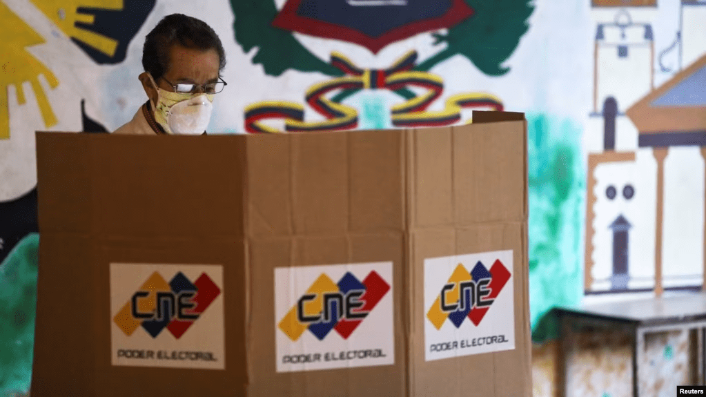 ARCHIVO - Un hombre parado frente a una cabina de votación en un colegio electoral durante las elecciones parlamentarias en Caracas, Venezuela, en diciembre de 2020.