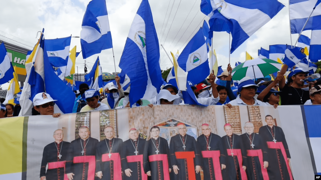 ARCHIVO - Manifestantes antigubernamentales sostienen una pancarta con un grupo de cardenales católicos, y una cita del papa Juan Pablo II en Managua, Nicaragua, el 28 de julio de 2018.
