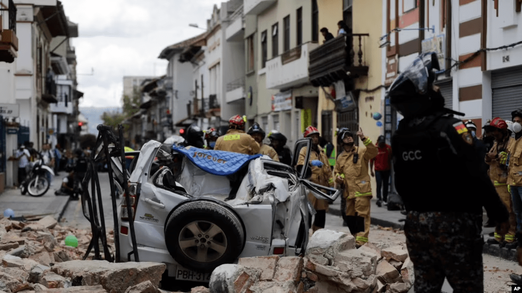 Un policía junto a un automóvil aplastado por los escombros después de que un terremoto sacudiera Cuenca, Ecuador, el sábado 18 de marzo de 2023. (AP Foto/Xavier Caivinagua)