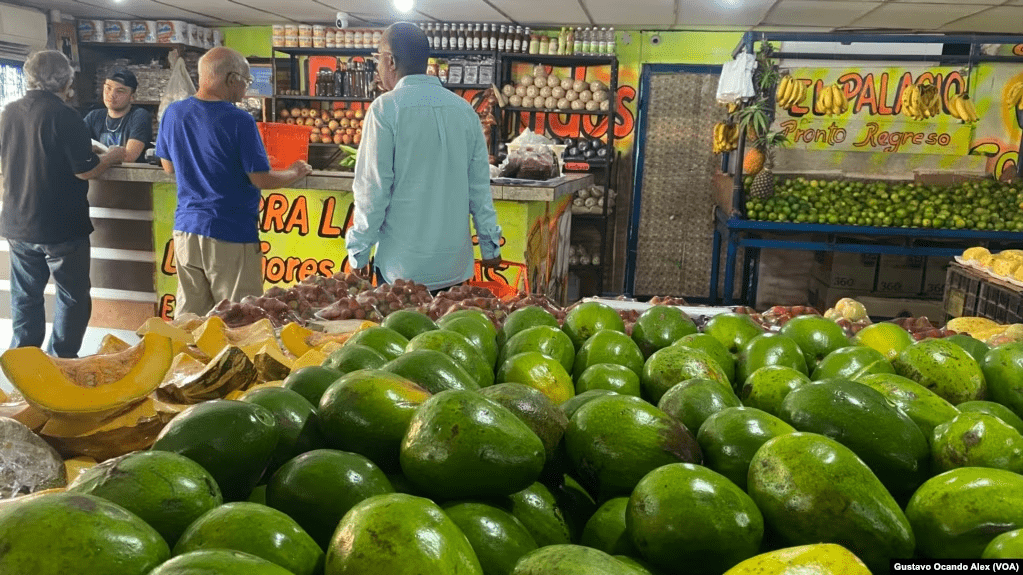 Clientes se aprestan para pagar sus compras de comida en una venta de frutas, vegetales y víveres en Maracaibo, Venezuela, el 13 de julio de 2023. Expertos hablan hoy de una recesión.