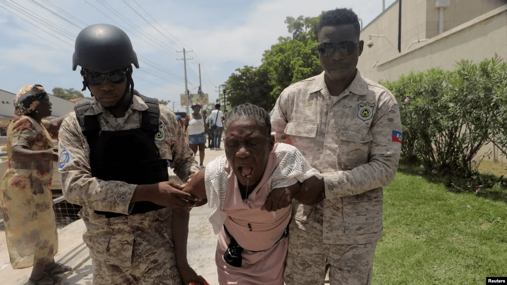 Oficiales de la Policía Nacional de Haití ayudan a una mujer afectada por gases lacrimógenos después de que la policía desalojara a personas que huían de la amenaza de bandas armadas, frente a la Embajada de Estados Unidos, en Puerto Príncipe, Haití, el 25 de julio de 2023.