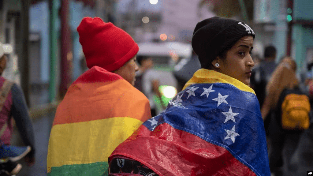 ARCHIVO - Una persona envuelta en una bandera venezolana camina con un grupo de migrantes que salen de la ciudad de Tapachula en el estado de Chiapas, México, a principios del 6 de junio de 2022.