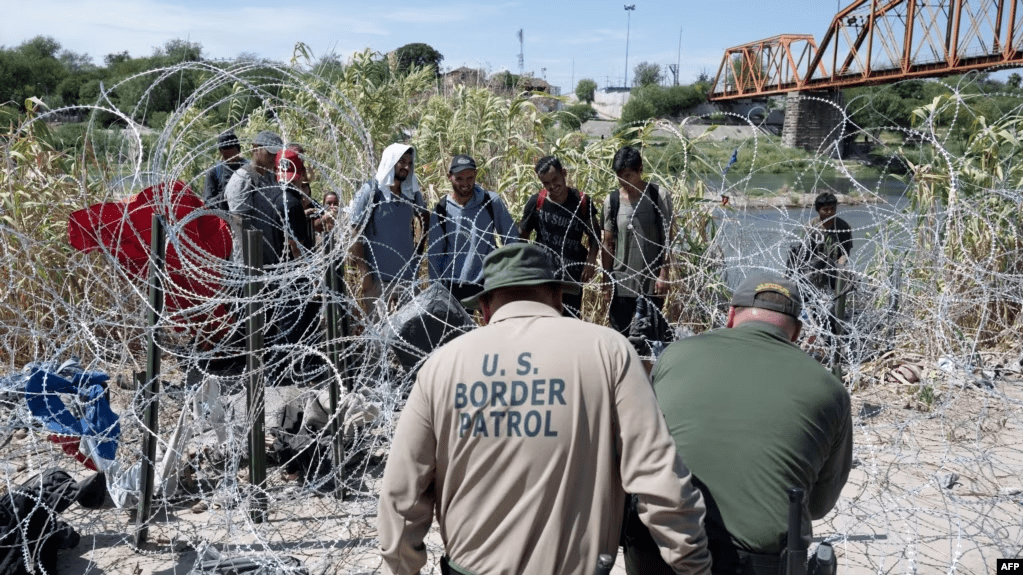 Migrantes venezolanos esperan a que la policía fronteriza de Estados Unidos corte el alambre que les impide El Paso luego de haber cruzado el Río Grande hacia Eagle Pass, Texas, el pasado 24 de septiembre. Las autoridades arrestaron a un presunto miembro de El Tren de Aragua.