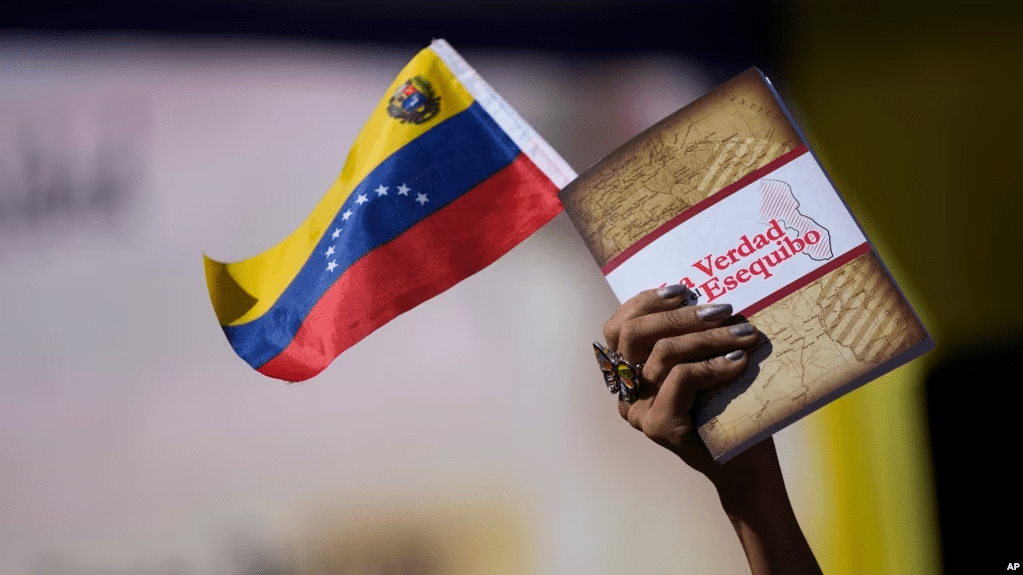 Una mujer sostiene una bandera venezolana y un libro sobre el Esequibo en Caracas, el pasado 29 de noviembre de 2023.