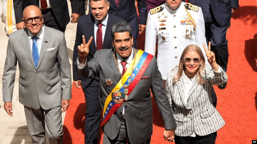 El presidente venezolano Nicolás Maduro y su esposa, Cilia Flores, saludan a su entrada al Palacio Federal Legislativo, en Caracas, este lunes, para presentar su memoria y cuenta anual. Les acompaña el presidente del parlamento, Jorge Rodríguez, a la izquierda en la fotografía.