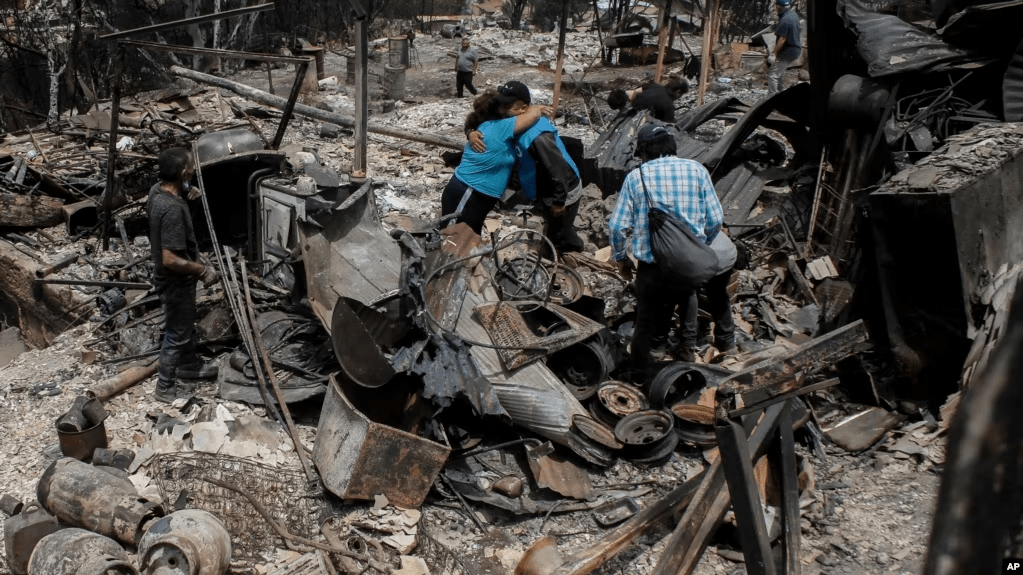 Residentes se abrazan entre los restos de casas calcinadas luego de que incendios forestales alcanzaron su vecindario, el domingo 4 de febrero de 2024, en Viña del Mar, Chile.