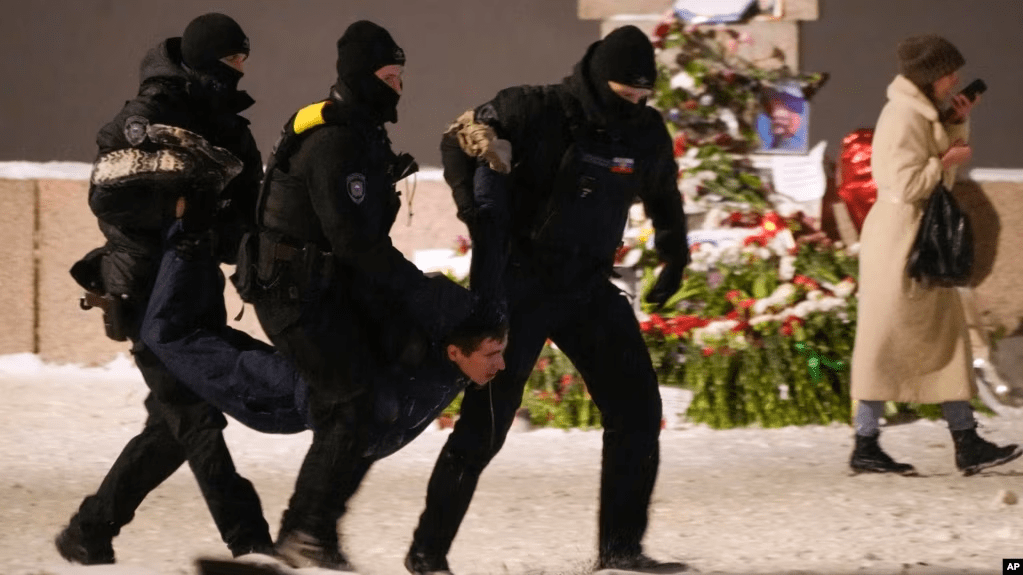 Agentes policiales detienen a un hombre que puso flores en un memorial del líder opositor ruso Alexei Navalny, en San Petesburgo, Rusia, el viernes 16 de febrero de 2024.