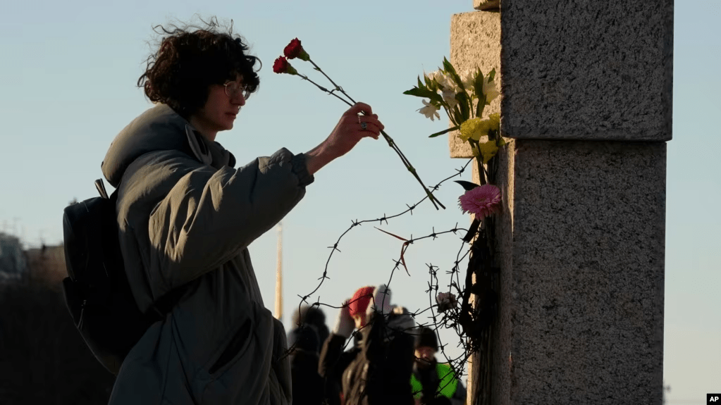 Una mujer deposita flores mientras la gente rinde homenaje a Alexei Navalny en el Memorial a las Víctimas de la Represión Política en San Petersburgo, Rusia, el 18 de febrero de 2024.