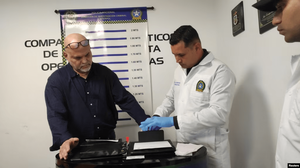Un policía toma huellas dactilares al ex comandante de las Autodefensas Unidas de Colombia (AUC), Salvatore Mancuso, luego de llegar a Colombia extraditado de Estados Unidos al Comando Aéreo de Transporte Militar (CATAM) en Bogotá, Colombia, el 27 de febrero de 2024.