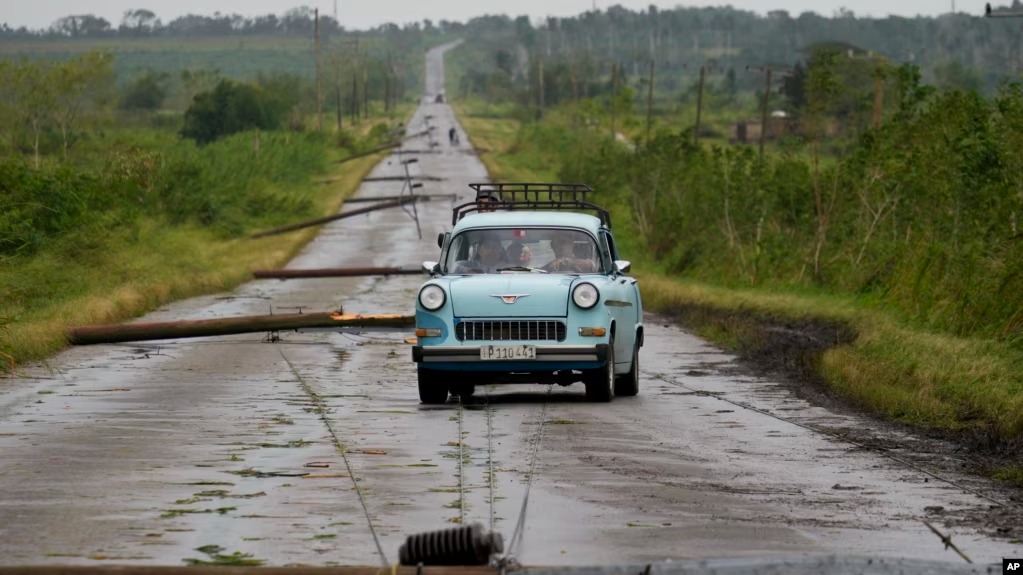 ARCHIVO - Un auto recorre una carretera llena de cables eléctricos caídos tras el paso del huracán Rafael en San Antonio de los Baños, Cuba, el 7 de noviembre de 2024.